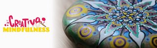 Mit Mandala bemalter Stein, darüber das Logo Creative Mindfulness mit einem Pinsel geschrieben