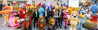 Many colorful mascots and people posing together in an exhibition hall.
