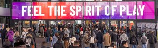 Eingang der Spielwarenmesse mit dem Schriftzug „FEEL THE SPIRIT OF PLAY“ und vielen Besuchern.