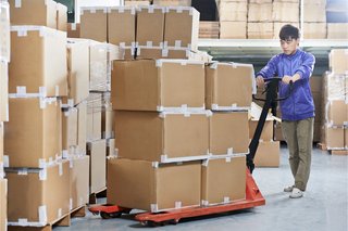 Paketlager, ein Lagermitarbeiter, der mit einem Hubwagen Pakete verschiebt