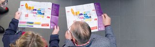 Two trade visitors planning their visit with the colorful hall maps of Spielwarenmesse