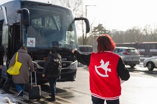 Trade fair visitors boarding the Spielwarenmesse bus, assisted by staff wearing Spielwarenmesse vest