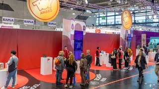 ToyAward-Ausstellungsbereich mit Besuchern und Präsentationsinseln.