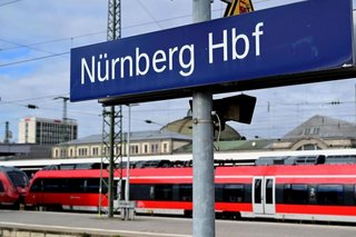 Regional train on the platform at Nuremberg Central Station with a sign reading “Nürnberg Hbf”