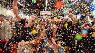 Bunte Konfetti-Party mit feiernden Menschen auf der Messe.