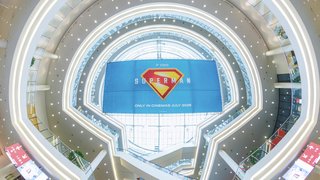 Large Superman movie poster hangs in modern, circular atrium of an exhibition hall.